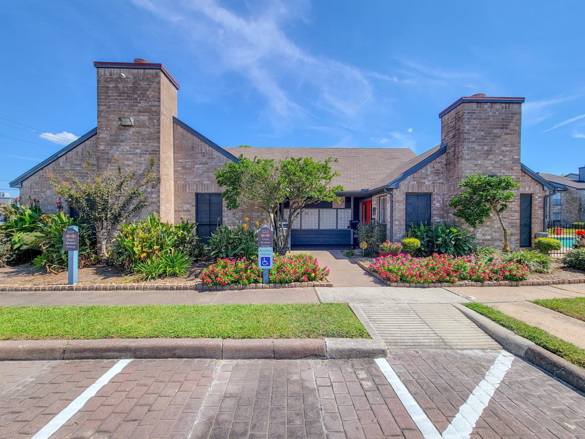 Brick leasing office entrance with flowering landscaped beds
